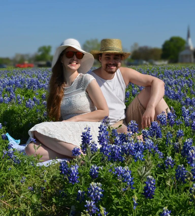 Couple sitting together in a Texas bluebonnet field on a sunny day