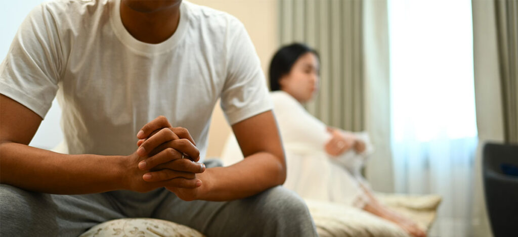 image of a man sitting away from wife, contemplating whether a marriage can survive infidelity