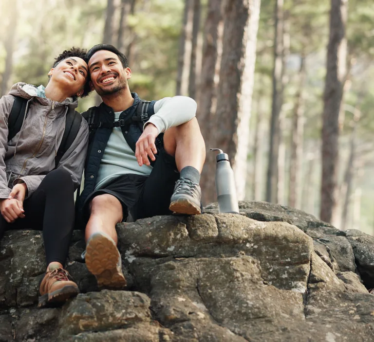 Couple resting together on a hike in a sunny pine forest